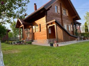 a large wooden house with a grass yard at Drvena kuća Marta in Belaj