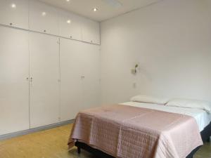 um quarto branco com uma cama e armários brancos em Habitaciones con baño compartido en Departamento Mid Century Modern em Mendoza