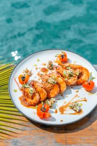 a plate of shrimp on a table next to a pool at Bambuda Bocas Town in Bocas del Toro