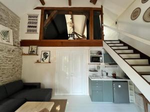 una pequeña sala de estar con una escalera y una cocina en La Passerelle en Saint-Hilarion