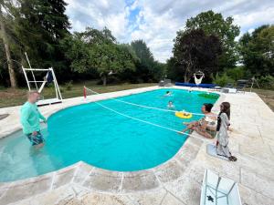 a group of people standing around a swimming pool at La Passerelle in Saint-Hilarion