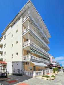 un edificio alto y blanco con balcones blancos. en Hotel Exarhos, en Paralia Katerinis