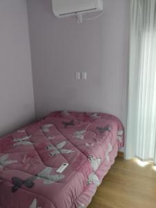 a bed in a room with a pink comforter at Los naranjos in Reconquista