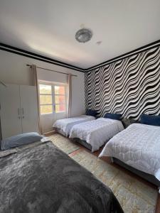 um quarto com 2 camas e uma parede listrada em Banana Surf House em Tamri