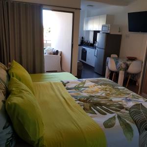 a bedroom with a bed with a yellow blanket on it at Tehautahi Cozy Lodge 2 in Papeete