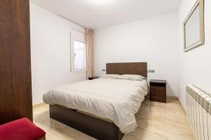 a bedroom with a white bed and a red chair at Mar & Cunit in Cunit