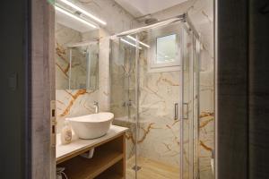 uma casa de banho com um lavatório e uma cabina de duche em vidro. em Molos Beachfront Apartments in Diakopto em Diakopto