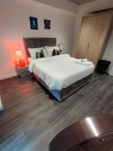 a bedroom with a large bed and a wooden floor at Immaculate 3-Bed Apartment Homes in London in London