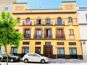 un edificio amarillo con dos coches estacionados frente a él en Un espacio diferente en Triana., en Sevilla