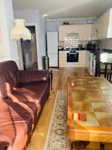 - un salon avec un canapé en cuir et une table dans l'établissement Crosby lovely refurbished flat, direct garden access; Wifi, à Crosby
