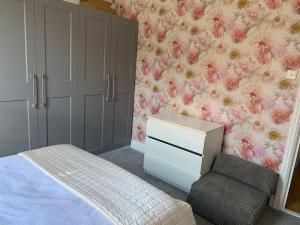 - une chambre avec un lit, une commode et une chaise dans l'établissement Crosby lovely refurbished flat, direct garden access; Wifi, à Crosby