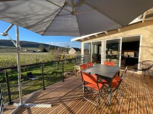 a wooden deck with a table and chairs and an umbrella at La Maison Fonteny, Gevrey Chambertin in Gevrey-Chambertin