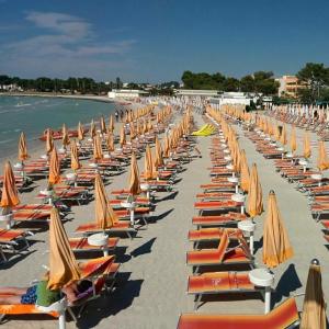a bunch of chairs and umbrellas on a beach at Colori Salentini Appartamento CORALLO in Sant'Isidoro