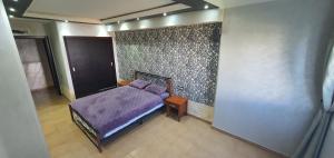 a bedroom with a purple bed and a wall at Kabila vista n4 vue piscine in M'diq