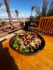 een bord salade op een tafel bij het strand bij Sukoon Camp in Nuweiba