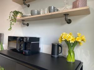 a black counter with a vase of yellow flowers and a microwave at The Nook @ Winchester. in Winchester