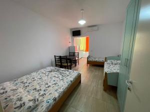 1 dormitorio con 2 camas, mesa y sillas en Vila Muça, en Shëngjin