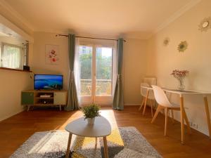 uma sala de estar com uma mesa e uma televisão em Maisons Alfort - Cosy appartement em Maisons-Alfort