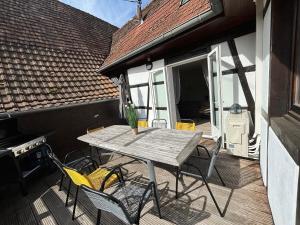 ein Holztisch und Stühle auf einer Terrasse in der Unterkunft Gîte de la Fontaine Charmante maison au cœur de Beblenheim - Route des vins in Beblenheim