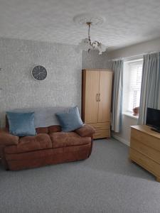 a living room with a brown couch and a television at Ocean View in Bushmills