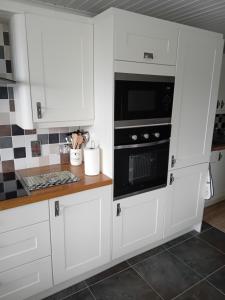 a kitchen with white cabinets and a microwave at Ocean View in Bushmills