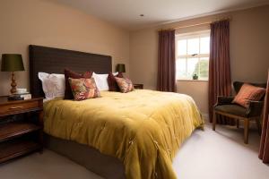 1 dormitorio con 1 cama con colcha amarilla y ventana en Risingham House, en West Woodburn