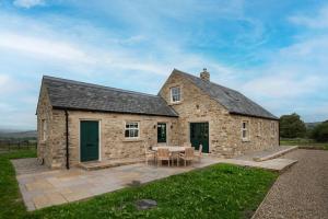 a stone house with a table and chairs in front of it at Risingham House in West Woodburn