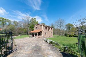 an old brick house with a gate in a yard at La Cabaña del Arroyo Pasiego in Selaya