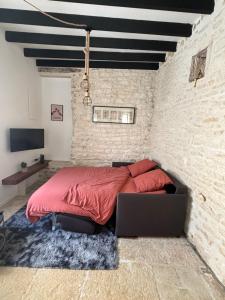 1 dormitorio con 1 cama en una pared de ladrillo en La maison de pierres, en Chablis