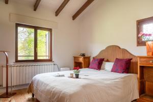 a bedroom with a large white bed with red pillows at La Cabaña del Arroyo Pasiego in Selaya