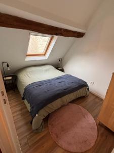 1 dormitorio con 1 cama con ventana y alfombra en La maison de pierres, en Chablis