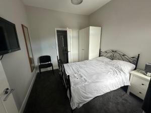- une chambre avec un lit, une télévision et une chaise dans l'établissement Colville Apartments, à Peterborough