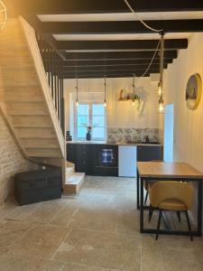 cocina y comedor con mesa y escaleras en La maison de pierres, en Chablis