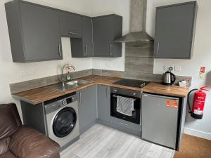 Il comprend une cuisine équipée d'un évier et d'un lave-linge. dans l'établissement Colville Apartments, à Peterborough