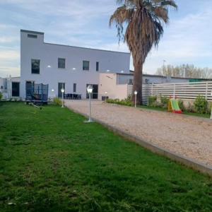 a large white building with a palm tree in front of it at B&B Le perle fg in Marconia