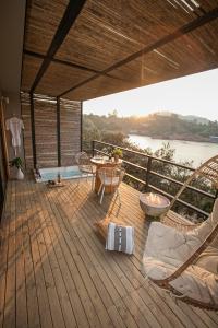 a deck with a table and chairs and a view of a river at La Pausa Hotelbistro in Guatapé