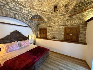 a bedroom with a bed in a stone wall at Doda Guest House in Gjirokastër