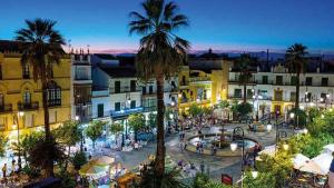 a town with a plaza with a fountain and palm trees at Brisas del Guadalquivir in Sanlúcar de Barrameda