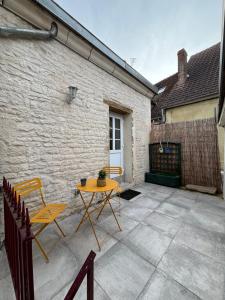 un patio con mesa y sillas frente a un edificio en La maison de pierres, en Chablis