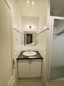 uma casa de banho branca com um lavatório e um espelho em Maisons Alfort - Cosy appartement em Maisons-Alfort
