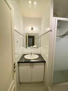 a white bathroom with a sink and a mirror at Maisons Alfort - Cosy appartement in Maisons-Alfort