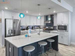 a kitchen with white cabinets and a large island with bar stools at blu #606 Luxury 2 Bd Beachfront Condo in Fort Walton Beach