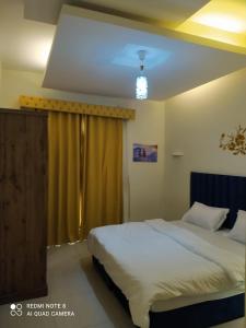 1Bedroom Furnished Apartment في دبي: غرفة نوم بسرير وستارة صفراء