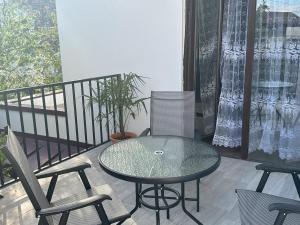 提比里斯的住宿－Three Palms Guest House，阳台上的玻璃桌子和椅子