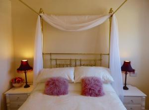 Una cama blanca con dos almohadas rosas. en Ferienhaus für 2 Personen und 1 Kind in Slaithwaite, England West Yorkshire en Slaithwaite