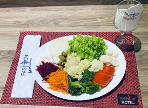 einen Teller mit Gemüse auf einem Tisch mit einem Glas in der Unterkunft Motel Fashion ABC 4 in Santo André