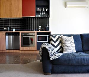 a blue couch in a living room with a kitchen at Daylesford Spa Villa One in Daylesford