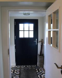 una puerta negra en un pasillo con suelo a cuadros en Heather Cottage and Shepherds Hut en Knock