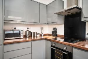 una cocina con armarios blancos y electrodomésticos de acero inoxidable en Private En-suite Room - Shared Living space & Kitchen - Wakefield - Central, en Wakefield