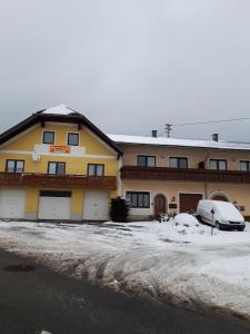 烏爾里希斯貝格的住宿－Ferienhaus für 10 Personen in Ulrichsberg, Oberösterreich Mühlviertel，一座有雪盖的建筑,前面有汽车停放